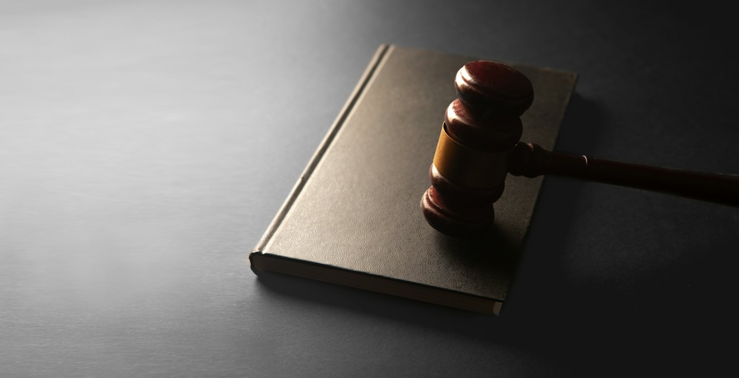 Wooden gavel rests on a closed legal book.