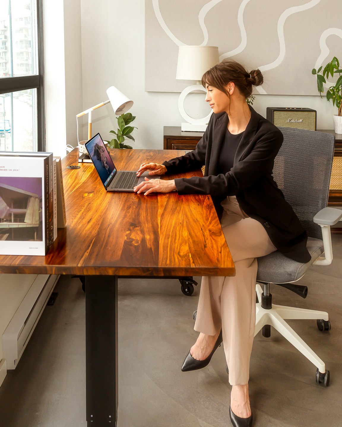 Woman working on a laptop at a wooden desk.