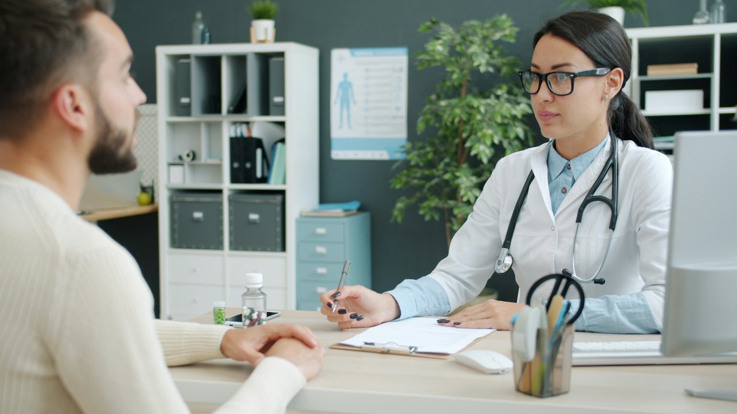 Doctor with pen consulting patient in office.