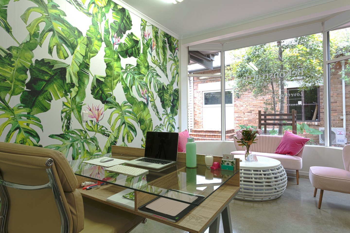 Modern office with a wooden desk and floral wall mural.